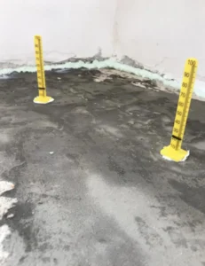 Detailní pohled na žluté plastové nivelační terčíky s měřítkem osazené na betonovém podkladu.
