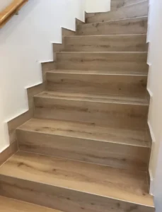 Kompletní realizace vinylového schodiště Moduleo s bočním soklem v přírodním dekoru – práce od ateliéru podlahového designu.