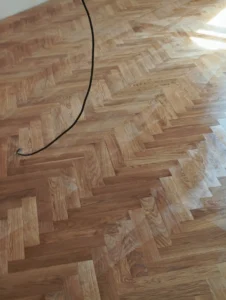 Detailní textura vybroušených dřevěných parket ve vzoru stromečku – precizní práce, kterou odvádějí podlaháři z Ostravy.