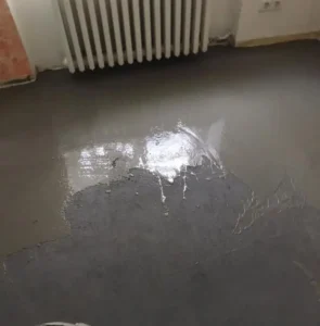 Lokální vysprávka podkladu nivelační hmotou pod radiátorem před pokládkou PVC.