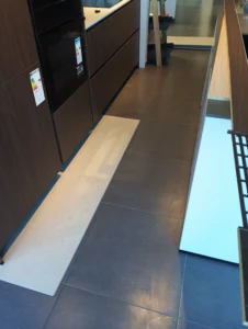 Pokládka vinylové podlahy BerryAlloc pod tmavou kuchyňskou linku v SIKO Ostrava.