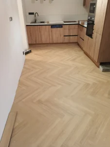 Pokládka vinylové podlahy se vzorem rybí kost - herringbone v kuchyni s detailem u dřevěné kuchynské linky podlahář Ostrava