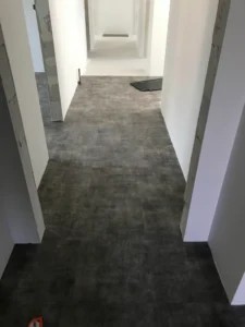 Pokládka tmavě šedé vinylové podlahy v uzké chodbě mezi místnostmi - realizace Ostrava