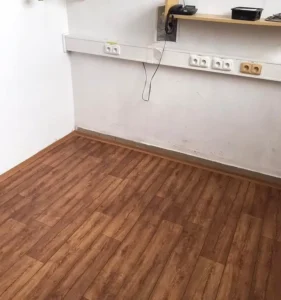 Detail pokládky PVC Ambient v dekoru dřeva u stěny se zásuvkami, realizace Veolia Ostrava.