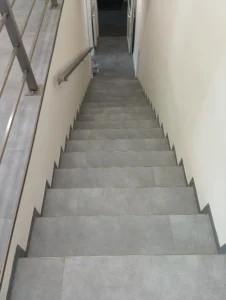 Celkový pohled na schodiště obložené zátěžovým vinylem Gerflor s bočním soklováním v komerčním prostoru v Ostravě