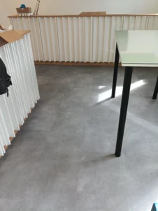 Detail zátěžových vinylových dílců Gerflor v šedém dekoru u recepčního pultu v Ostravě